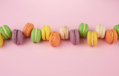 Açık pembe arka planda, çok renkli, yuvarlak, fırında makarna kekleri.