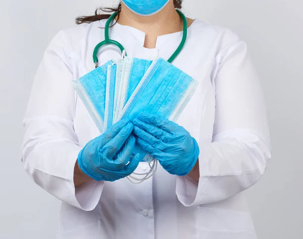 Női Orvos Fehér Kabátban Maszkban Tart Egy Halom Védő Maszk — Stock Fotó