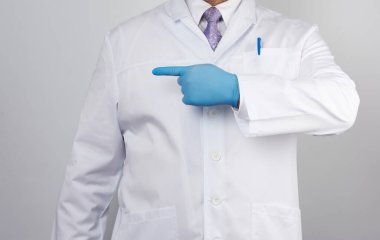 Düğmeli, elinde mavi steril eldiven olan beyaz önlüklü sağlıkçı adam, şüpheliyi işaret eden el hareketi gösteriyor, beyaz arkaplan.