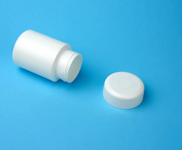 open empty white plastic container for pills lies on a blue background, top view
