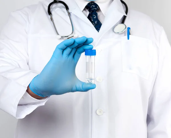 Beyaz önlüklü ve mavi steril lateks eldivenli doktor dışkı analizi için plastik bir kavanoz tutuyor.