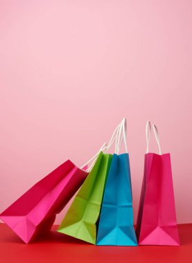 Alışveriş için dört boş kağıt torba ve beyaz saplı hediyeler pembe-kırmızı arka planda duruyor, boşluğu kopyala