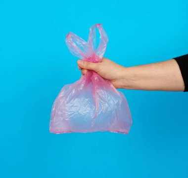 Mavi arka planda boş bir pembe plastik poşet, plastiğin reddedilmesi ve eko-ambalaja geçiş kavramı