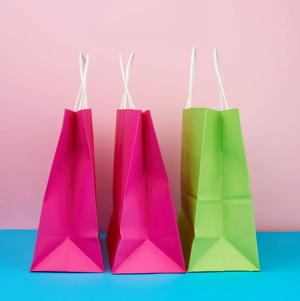 ピンクブルーの背景に白いハンドル付きのショッピングやギフトのための空の多色の紙袋 コピースペース — ストック写真