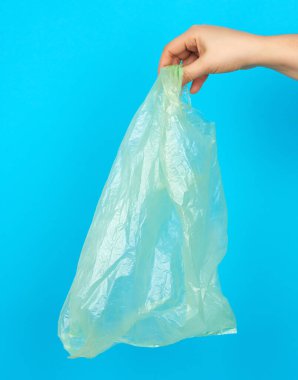 Mavi zemin üzerinde boş bir yeşil plastik torba, plastik reddedilme konsepti ve eko-ambalaja geçiş
