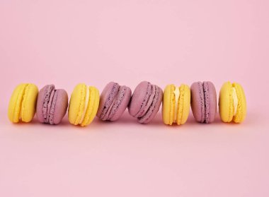 Açık pembe arka planda, çok renkli, yuvarlak, fırında makarna kekleri.