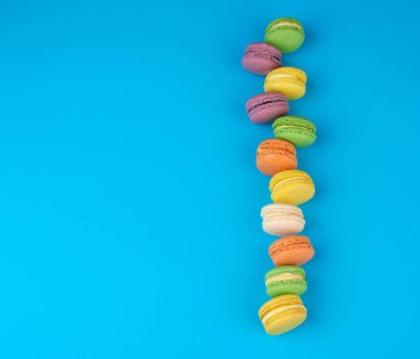 krem ile yuvarlak çok renkli pişmiş makarnalar mavi bir arka plan üzerinde bir çizgi yalan, düz yatıyordu, kopyalama alanı