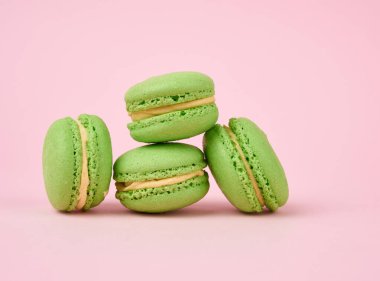 Bir yığın yeşil yuvarlak badem unlu kek kremalı makarna pembe arka planda, lezzetli bir pasta