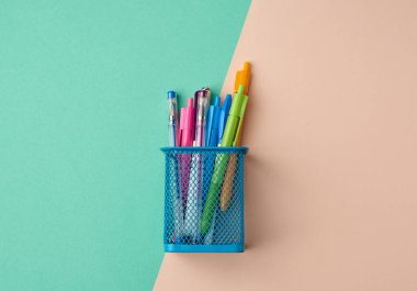 Kırtasiye için mavi metal kap, içinde çok renkli plastik kalemler, üst görünüm