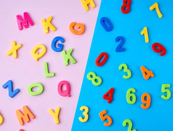 plastic multi-colored numbers and letters of the English alphabet on a blue-violet background, top view, back to school