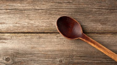 Eski tahtalardan gri ahşap bir yüzey üzerinde eski boş kahverengi kaşık, üst görünüm