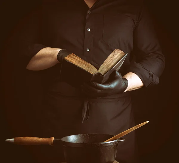 Cozinheiro Masculino Uniforme Preto Mantém Velho Livro Receitas Com Receitas — Fotografia de Stock