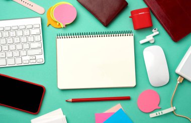 kağıt defter, klavye, kablolu güç bankası, boş ekranlı kırmızı akıllı telefon, kulaklıklar, boş kağıt kartvizitler ve yeşil arka planda kablosuz fare, işyeri, üst görünüm