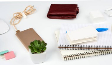 defterler, kalem, kartvizit yığını, kahverengi deri cüzdan ve elektrik kablosu beyaz bir masa, işyeri