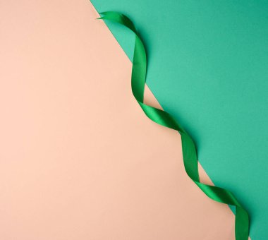 kıvrımlı ipek yeşil kurdele yeşil-bej arka plan, üst görünüm, kırpılmış uç