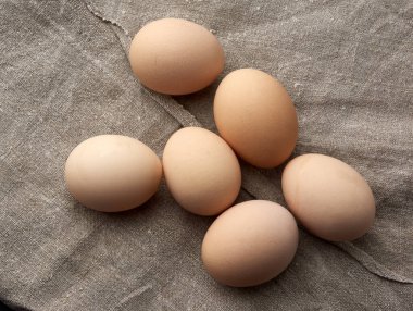 Kırık çiğ kahverengi tavuk yumurtalarının hepsi gri keten peçetede, üst tarafta.