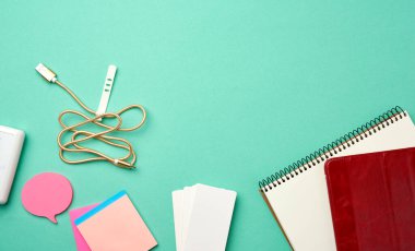 Boş beyaz sayfalı, kablosuz kulaklıklı, yeşil arka planda şarj cihazlı, üst görünümde, boşluk kopyala