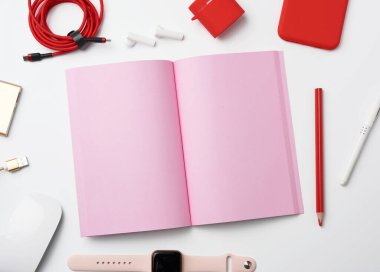 Pembe kağıt defter, kablolu elektrik bankası, kırmızı akıllı telefon, kulaklık, kablosuz fare, beyaz arka planda akıllı saat, işyeri, üst görüş