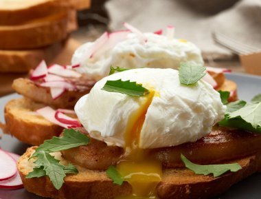 Kızarmış ekmek üzerine kızarmış ekmek, haşlanmış yumurta, yeşil roka ve turp yaprakları kahverengi tahta üzerinde sabah kahvaltısı, yakın çekim.