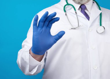 Doktor eli mavi steril lastik eldiven takıyor. Elinde mavi bir nesne var.