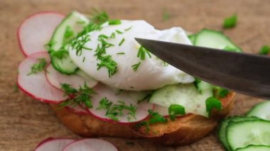 Bıçaklı bir el, haşlanmış tavuklu yumurtalı sandviç, kızarmış ekmek, yeşil soğan serpiştirilmiş, lezzetli bir sabah kahvaltısı, haşlanmış yumurtanın sarı sarısı.