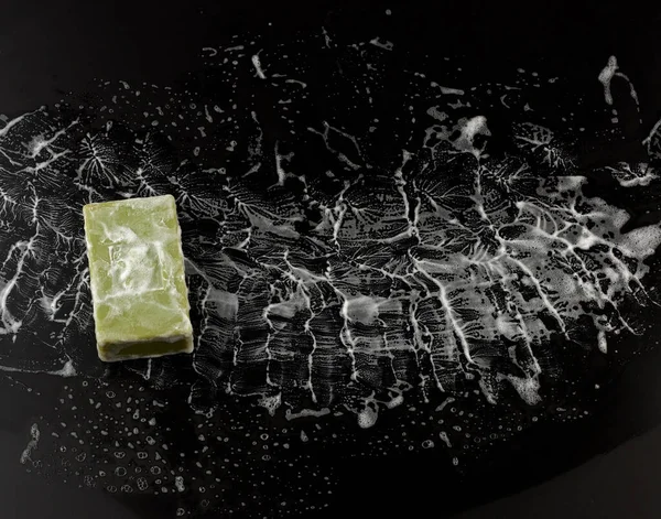 white soap foam and green soap on a black background, top view, concept of cleanliness, antibacterial