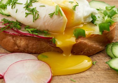 Kızarmış beyaz ekmek dilimli sandviç haşlanmış yumurta, dereotu ve yeşil soğan dilimleri ile yumurta sarısı yumurtadan akar.