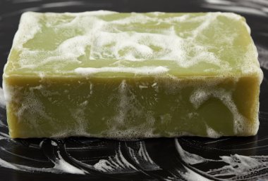 Siyah arka planda beyaz köpüklü doğal yeşil sabun kalıbı, hijyen kavramı, kapat.
