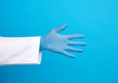 Beyaz önlüklü doktor, mavi lateks eldivenli. Mavi arka planda el sıkışmak için elini çekiyor.