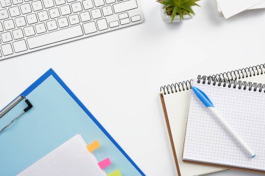 Beyaz kablosuz klavye, bir yığın defter, saksılarda yeşil bitkiler ve bir fare, serbest çalışan birinin çalışma yeri, iş adamı. Beyaz tablo