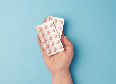 El ele tutuşan yuvarlak tablet paketleri, mavi arkaplan, üst görünüm