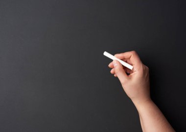Boş bir siyah tebeşir tahtasının arka planında beyaz bir tebeşir parçası var. Sunum konsepti, okula dönüş.