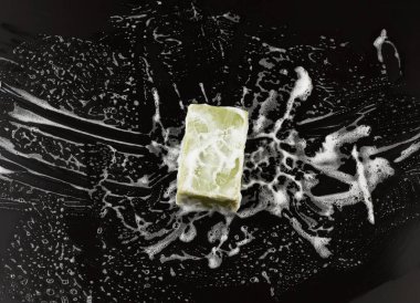 Siyah zemin üzerinde beyaz sabun köpüğü ve yeşil sabun, üst görünüm, temizlik konsepti, antibakteriyel