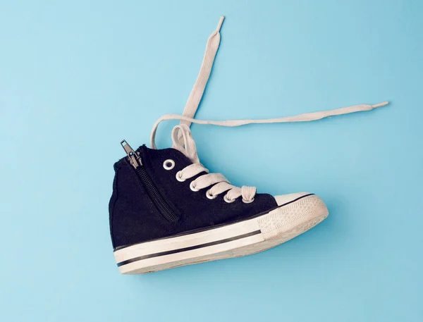 儿童黑色运动鞋 鞋底为橡胶 鞋带为白色 背景为蓝色 — 图库照片