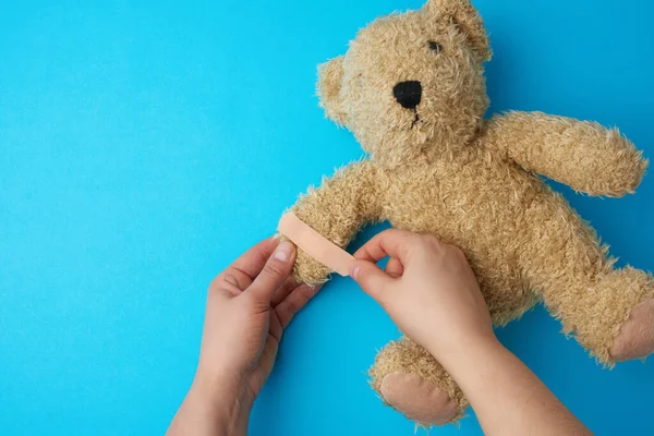 Dos Manos Sosteniendo Oso Peluche Pegando Yeso Adhesivo Sobre Una — Foto de Stock