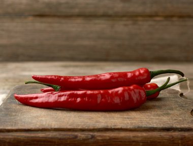 Kahverengi ahşap bir masada kırmızı biber, gri masa, yakın çekim.