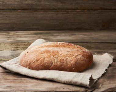 Mutfak gri peçetesinin üstünde yuvarlak çavdar ekmeği, üst manzara.