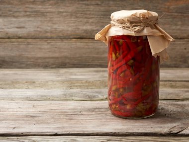 Ahşap arka planda kırmızı biberli turşulu cam kavanoz, kapat, boşluğu kopyala