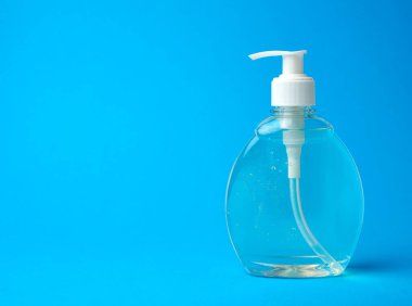 Mavi arka planda elleri dezenfekte etmek için kullanılan bir dezenfektan ile şeffaf plastik şişe.
