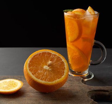  Limonata ile doldurulmuş portakal ve limon dilimli büyük bardak, siyah arkaplan.