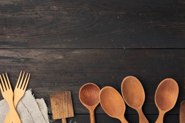 Tahtaların, üst manzaranın, mutfak arka planının kahverengi ahşap arka planında boş tahta kaşıklar, çatallar ve spatulalar.