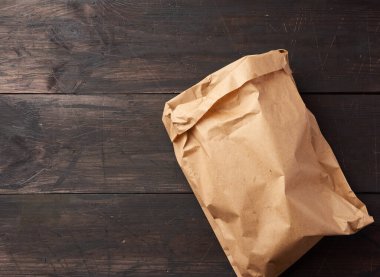 Kahverengi ahşap arka planda yiyecek ambalajı için açık kahverengi kese kağıdı, çevreyi kurtarmak için plastik torbaların reddedilmesi, üst görünüm