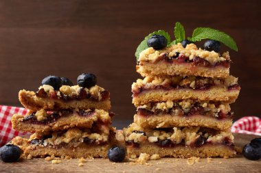 Ahşap bir tahtanın üzerinde mavi erikli fırınlanmış kare dilimler, lezzetli bir tatlı.