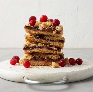 Beyaz ahşap bir tahtada mavi erikli kare dilimler, lezzetli bir tatlı, yakın plan.