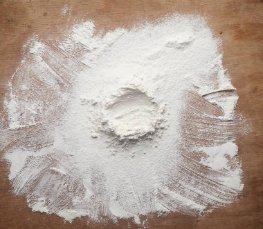 Kahverengi ahşap bir masaya saçılmış beyaz buğday unu, üst görüş, sıvı malzemeler için huni