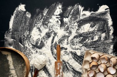 Serpilmiş beyaz buğday unu, ahşap merdane, yuvarlak elek ve tavuklu yumurta kabuğu kağıt tepside, üst manzara, mutfak arkaplanı