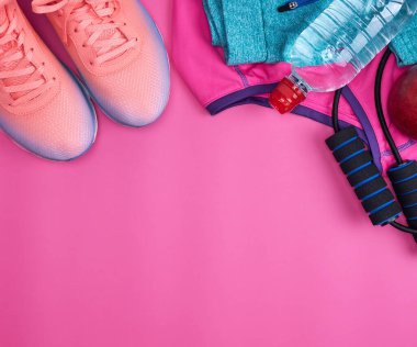 İp atlama, su şişesi, pembe spor ayakkabıları, spor kıyafetleri ve pembe arka plan, üst manzara, düz yatak.