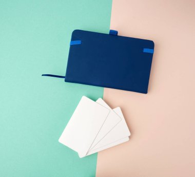 Yeşil bej arkaplan, tasarımcı için arkaplan üzerine dikdörtgen beyaz kartvizit ve mavi defter yığını