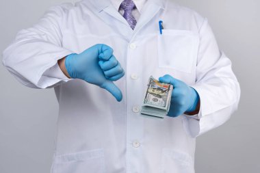 Mavi üniformalı doktor ve lateks eldivenli doktor bir elinde çok para tutuyor, diğer elinde kötü bir jest, rüşvet kavramı var. 