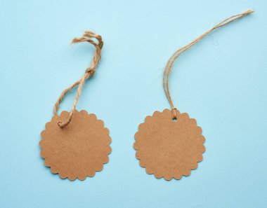 İple bağlanmış yuvarlak kahverengi kağıt etiket. Fiyat, hediye, mavi arka planda satış etiketi, kapat.